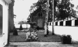 Blick (um 1980) in den Pfarrhof von Osten. Das Pfarrhaus am linken Rand. Die Friedhofsmauer hat man (ringsum)durch aufgesetzte Pfeiler und Eisengitter erhöht. Voraus das alte Konfirmandenhaus mit zugemauerter Tür.